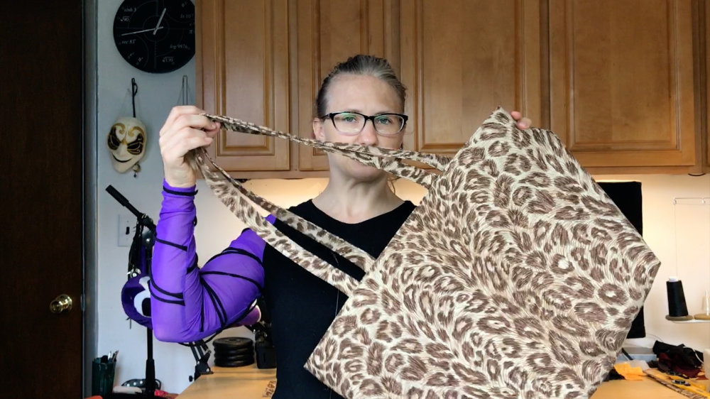 Holidng up a tote bag that is made from a leopard print drapery fabric.